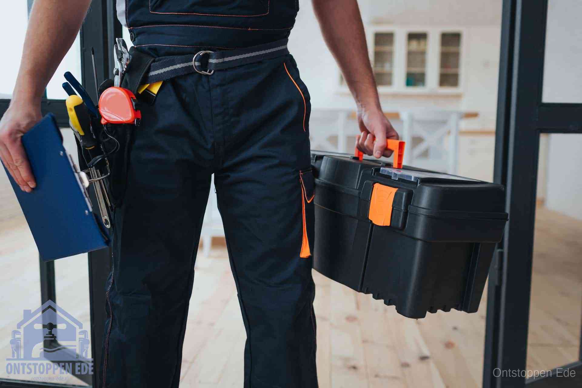 Een monteur met gereedschapsriem en klembord in een keuken, klaar om een transparante prijs voor het gootsteen ontstoppen in Ede te geven