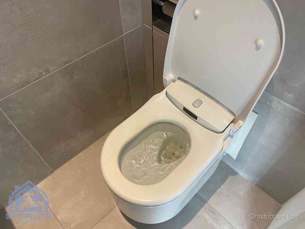 Een toiletpot vol troebel water met drijvend papier en restanten, de meest voorkomende oorzaak van een verstopte wc in Ede