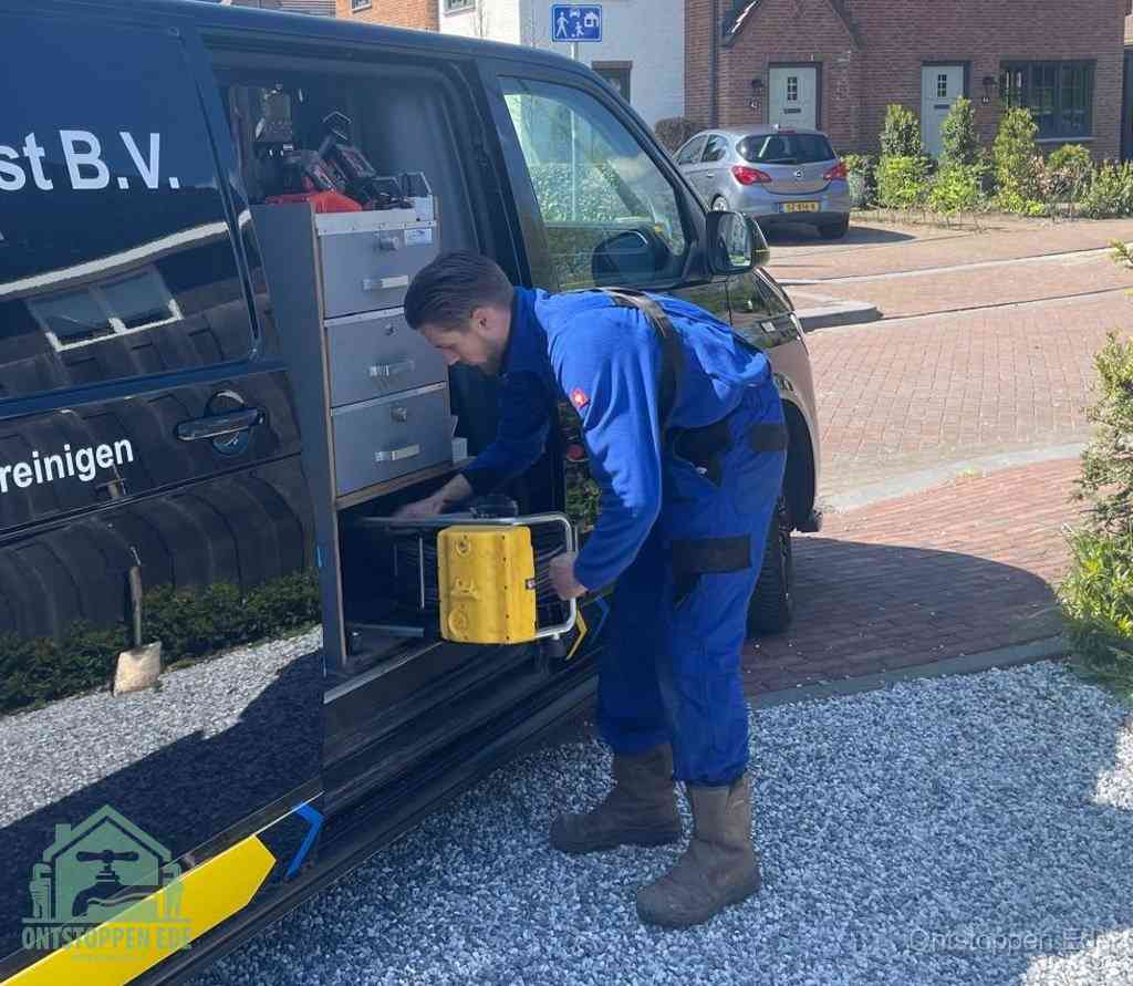Een monteur pakt buiten op de oprit gereedschap uit de bedrijfsbus, het moment om een professional in te schakelen voor een verstopte afvoer in Ede