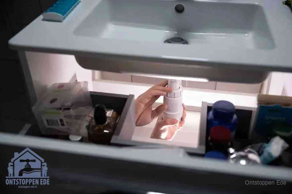Een pompfles met zeep boven een wastafel in de toiletruimte, de warm water en afwasmiddel-methode om de wc te ontstoppen in Ede