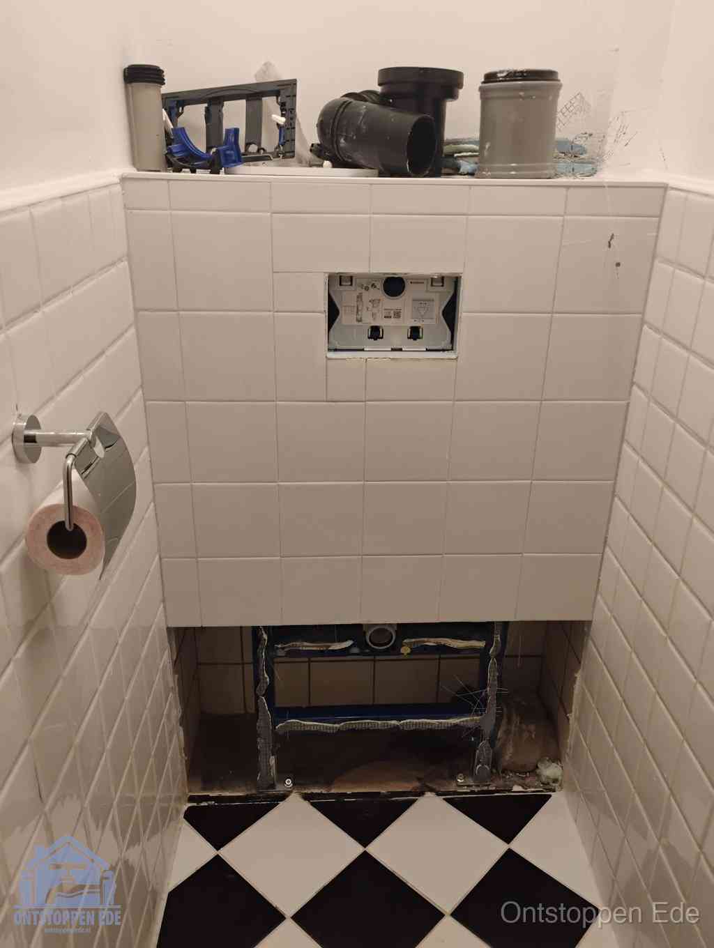 Een toiletruimte waar het hangtoilet en de inbouwreservoir-onderdelen zijn vrijgelegd voor onderhoud, periodiek nazicht voorkomt een wc-verstopping in Ede